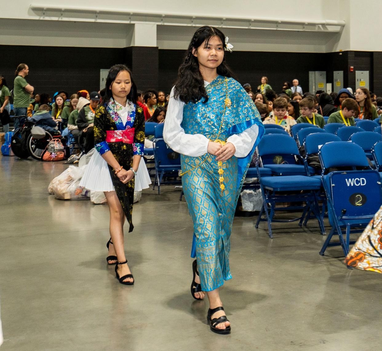 Milwaukee Academy of Chinese Language fifth-graders Kayia Vang, left, and Marra Chrara, right, walk in a cultural fashion show at the Milwaukee Public School World Fair.