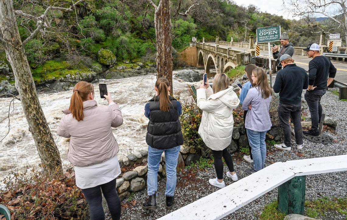 Visitors stop to photograph heavy storm runoff on the Kaweah River at the Pumpkin Hollow Bridge and the Gateway Restaurant and Lodge on Highway 198 in Three Rivers on Saturday, March 11, 2023.