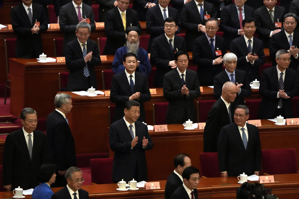 Chinese President Xi Jinping, center applauds near Chinese Premier Li Qiang, right, during the opening session of the Chinese People's Political Consultative Conference in the Great Hall of the People in Beijing, Monday, March 4, 2024. (AP Photo/Ng Han Guan)