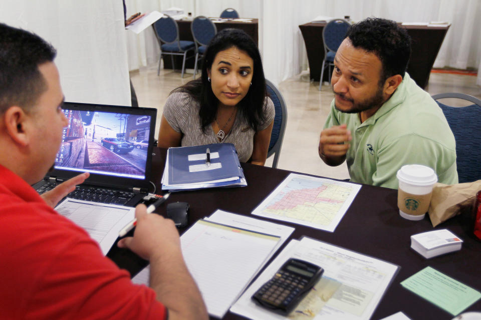 Michelle Ruiz (L) and Nilson Ruiz listen as Wells Fargo home mortgage consultant, Michael Carreras, helps the potential homeowners with their an application for a down payment assistant grant. (Credit: Joe Raedle, Getty Images)