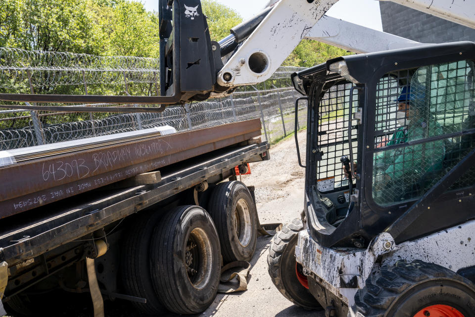 Workers unload steel beams beside a perimeter fence lined with razor wire at the former Arthur Kill Correctional Facility, Tuesday, May 11, 2021, in the Staten Island borough of New York. The facility was purchased by Broadway Stages in 2017 and has been transformed into a film and television studio. Much of the prison was preserved as a set, lending authenticity to scenes in productions. Five other sound stages are being built on the 69-acre site, giving production companies the ability to shoot entire projects. (AP Photo/John Minchillo)