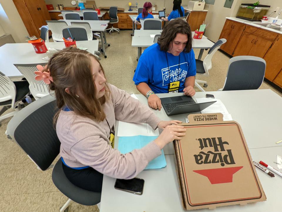 Isabella Hermansen, a sophomore at Olathe East High School, works with Ashton Harter, a senior at Stafford High School, on their pizza-box project to showcase what they've learned during their week at the Kansas Future Teacher Academy.