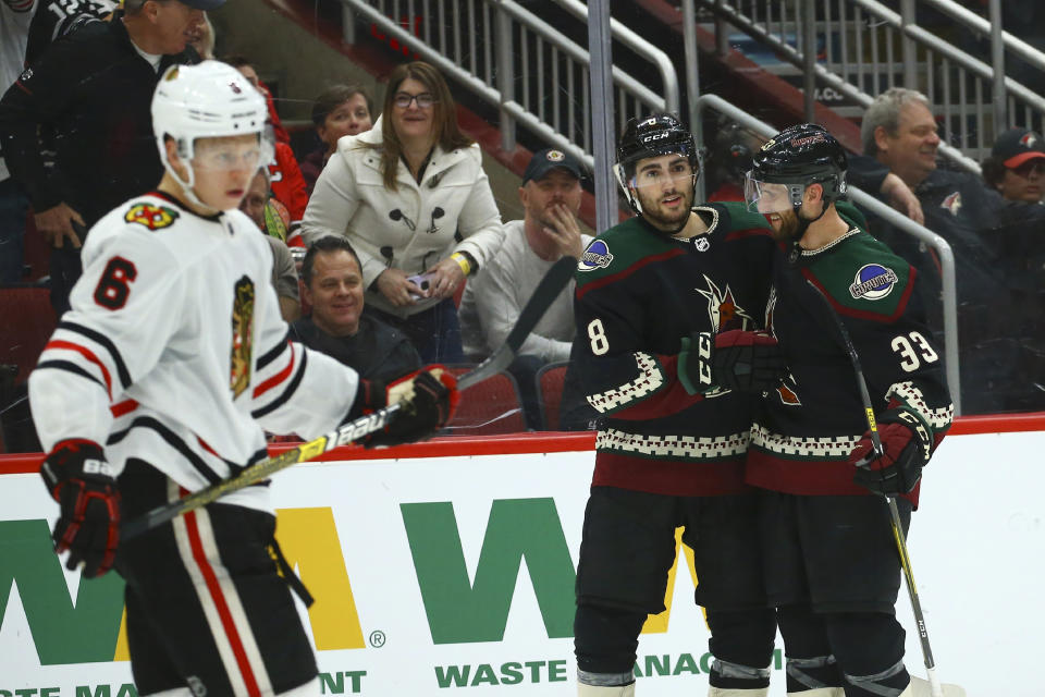 Arizona Coyotes center Nick Schmaltz (8) celebrates his goal with Coyotes defenseman Alex Goligoski (33) as Chicago Blackhawks defenseman Olli Maatta (6) skates past during the second period of an NHL hockey game Thursday, Dec. 12, 2019, in Glendale, Ariz. (AP Photo/Ross D. Franklin)