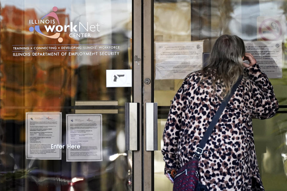 A woman checks information as information signs are displayed at IDES (Illinois Department of Employment Security) WorkNet center in Arlington Heights, Ill., Thursday, Nov. 5, 2020. Illinois reports biggest spike in unemployment claims of all states. (AP Photo/Nam Y. Huh)