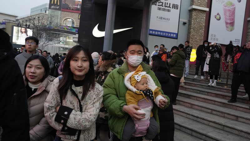 A man carries a child at a shopping mall in Beijing, Dec. 30, 2023. China’s population dropped by 2 million people in 2023 in the second straight annual drop as births fell and deaths increased.