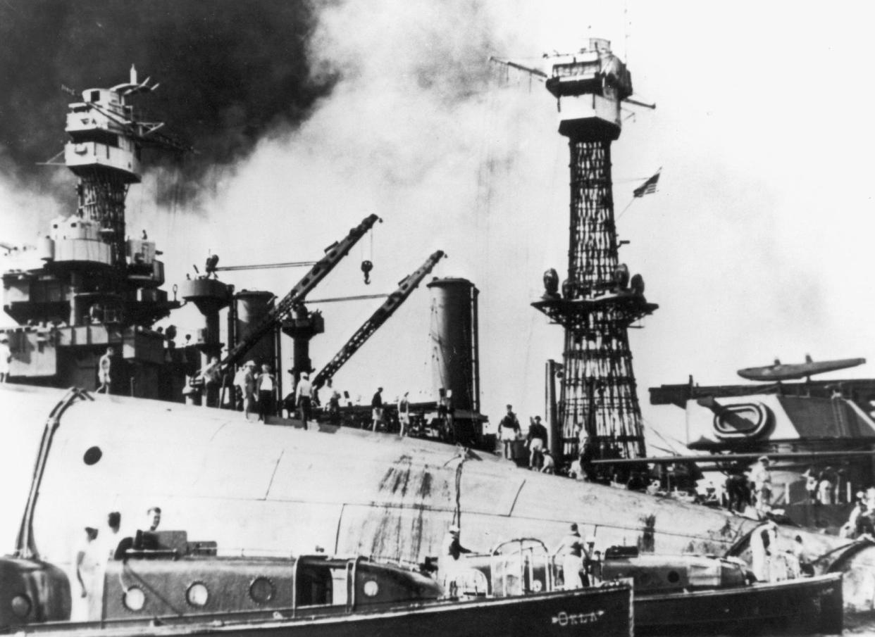 Rescue crews are shown working on the upturned hull of the USS Oklahoma, which was capsized in Pearl Harbor after being blasted by Japanese planes.  Holes were burned through the hull to permit the rescue of some men trapped below.  The USS Maryland is in the background,    12/7/1941