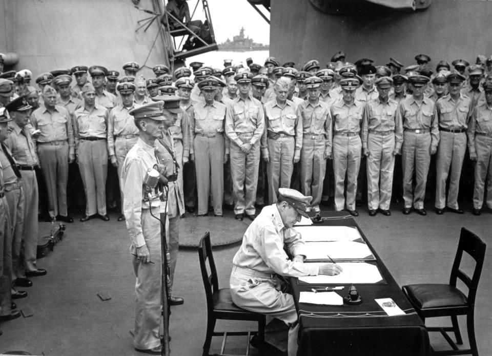 FILE - Gen. Douglas MacArthur signs the Japanese surrender documents on Sept. 2, 1945, aboard the USS Missouri in Tokyo Bay. Standing behind him are Lt. Gen. Jonathan Wainwright, left foreground, who surrendered Bataan to the Japanese, and British Lt. Gen. A. E. Percival, next to Wainwright, who surrendered Singapore, as they witness with other American and British officers the ceremony marking the end of World War II. Several dozen aging U.S. veterans, including some who were in Tokyo Bay on the day that ended World War II, will gather on the battleship in Pearl Harbor in September to mark the 75th anniversary of Japan's surrender. (U.S. Navy, File)