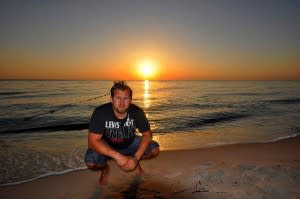 Man on the beach, with the sun setting behind him