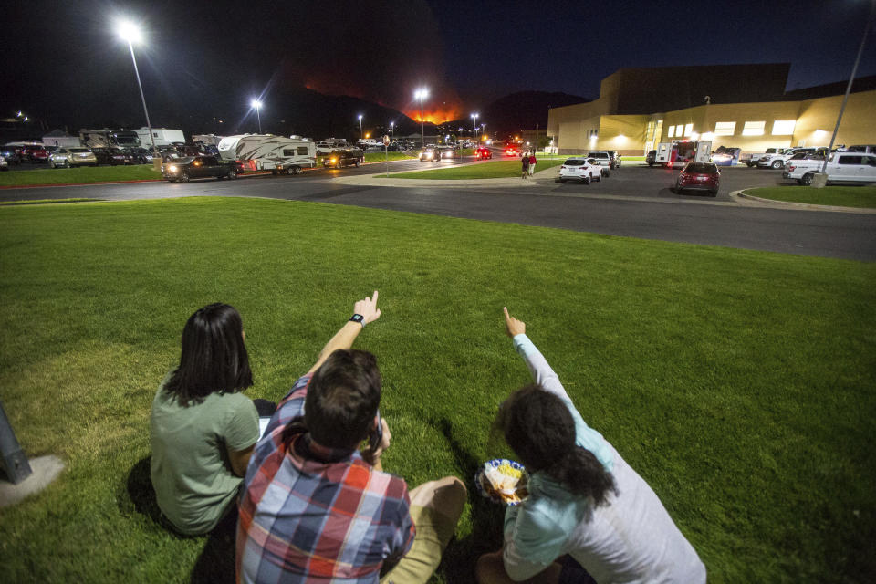 In this Thursday, Sept. 13, 2018, photo, residents watch a wildfire burning from outside Salem Hills High School in Salem, Utah. (Qiling Wang/The Deseret News via AP)