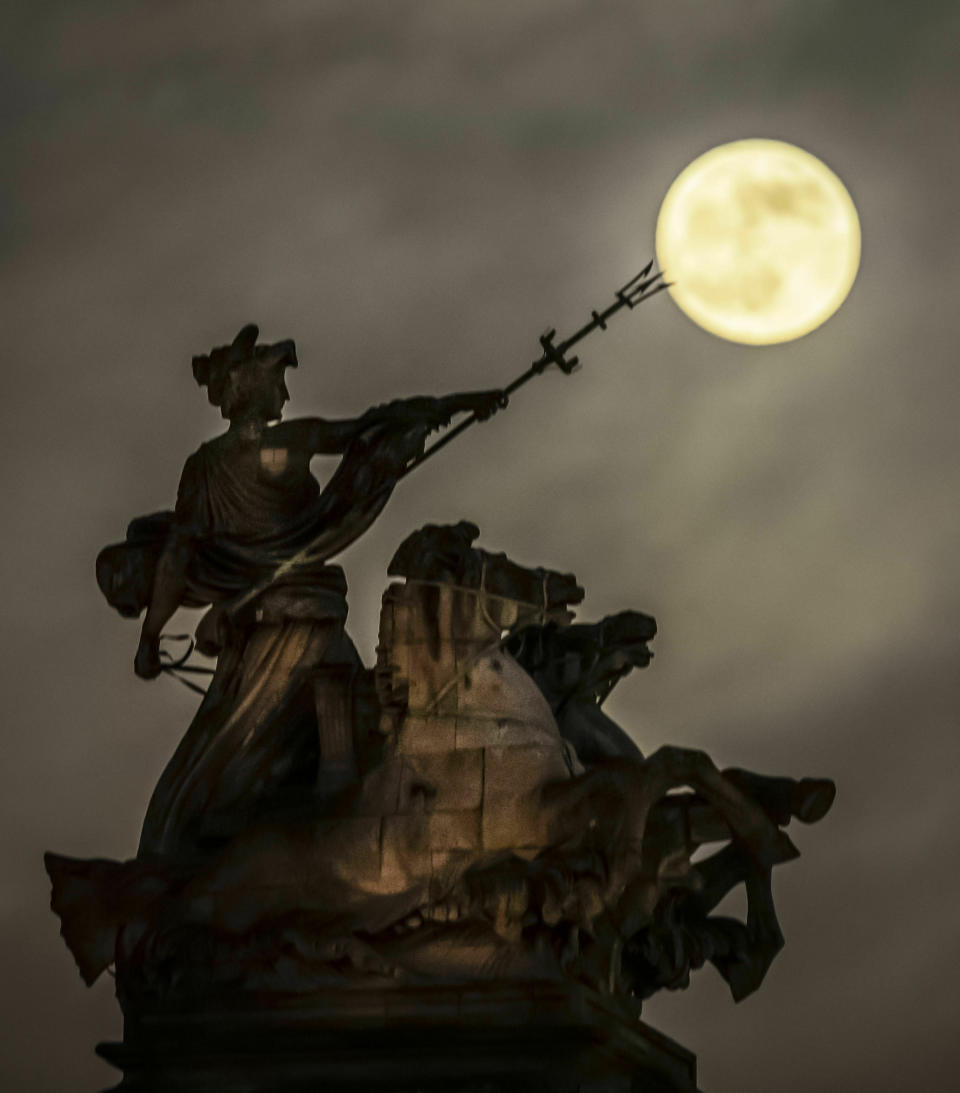 A blood moon, set to be the last of its kind for two years, rises above the 'Maritime Prowess' by Albert Hemstock Hodge on the Guild Hall ahead of the Lunar Eclipse, in Hull, England, Sunday, Jan. 20, 2019. (Danny Lawson/PA via AP)