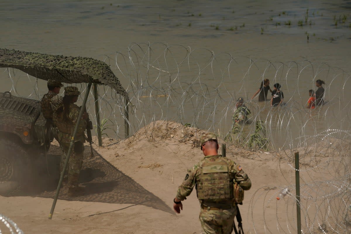 Guardsmen watch as migrants try to cross the Rio Grande from Mexico into the U.S. near in Eagle Pass, Texas, Tuesday, July 11, 2023 (Copyright 2023 The Associated Press. All rights reserved)
