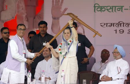 India's Congress party president Sonia Gandhi (C) lifts a plough given to her by the head of the party's Delhi branch Ajay Maken as Congress party vice president Rahul Gandhi (seated L) and former prime minister Manmohan Singh (R) look on during a farmers' rally at Ramlila ground in New Delhi April 19, 2015. REUTERS/Anindito Mukherjee