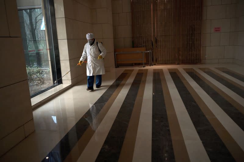 Worker Wang Fu wearing a face mask sprays disinfectant at an apartment's lobby in a residential compound, as the country is hit by an outbreak of the novel coronavirus, in Beijing