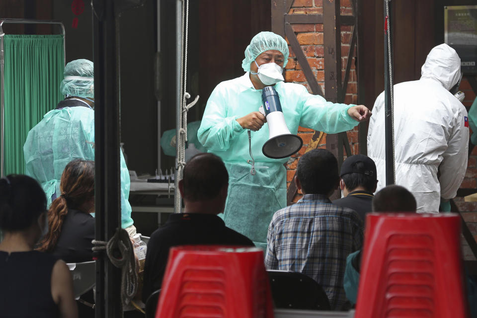 FILE - In this May 18, 2021, file photo, medical personnel wearing protective gear, guide people at a rapid coronavirus testing center after the infection alert rose to level 3 in Taipei, Taiwan. After a year of success, Taiwan is struggling with its largest outbreak since the pandemic began. When locally transmitted cases started being found in May 2021, it soon became clear that the central government was ill prepared not only to contain them, but to even detect them on a large scale due to a lack of investment in and a bias against rapid testing. (AP Photo/Chiang Ying-ying, File)