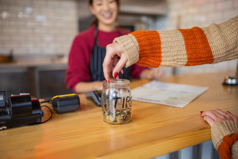 hand putting coins in a tip jar