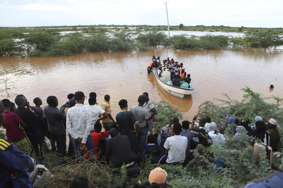 People cross a flooded area at Mororo, border of Tana River and Garissa counties, North Eastern Kenya, Sunday, April. 28, 2024. Heavy rains pounding different parts of Kenya have led to dozens of deaths and the displacement of tens of thousands of people, according to the U.N. (AP Photo/Andrew Kasuku)