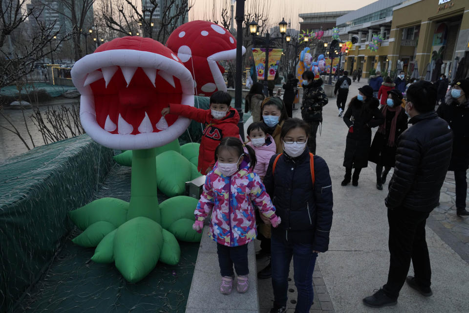 Visitors to a mall with a monster themed festival wears masks to protect from the coronavirus in Beijing Saturday, Dec. 26, 2020. Beijing has urged residents not to leave the city during the Lunar New Year holiday in February, implementing new restrictions after several coronavirus infections last week. (AP Photo/Ng Han Guan)