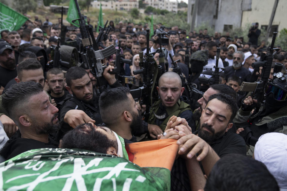 Mourners carry the body of Hamas local commander Mohammad Daraghmeh, 26, wrapped with a Hamas flag, during his funeral in the West Bank city of Tubas, Friday, April 12, 2024. Two Palestinians were killed early Friday in confrontations with Israeli forces in the Israeli-occupied West Bank, Palestinian medics and the Israeli military said. The Islamic militant group Hamas said one of those killed was a local commander. (AP Photo/Nasser Nasser)