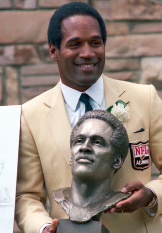 <p>Bettmann</p> O.J. Simpson with his NFL Hall of Fame trophy
