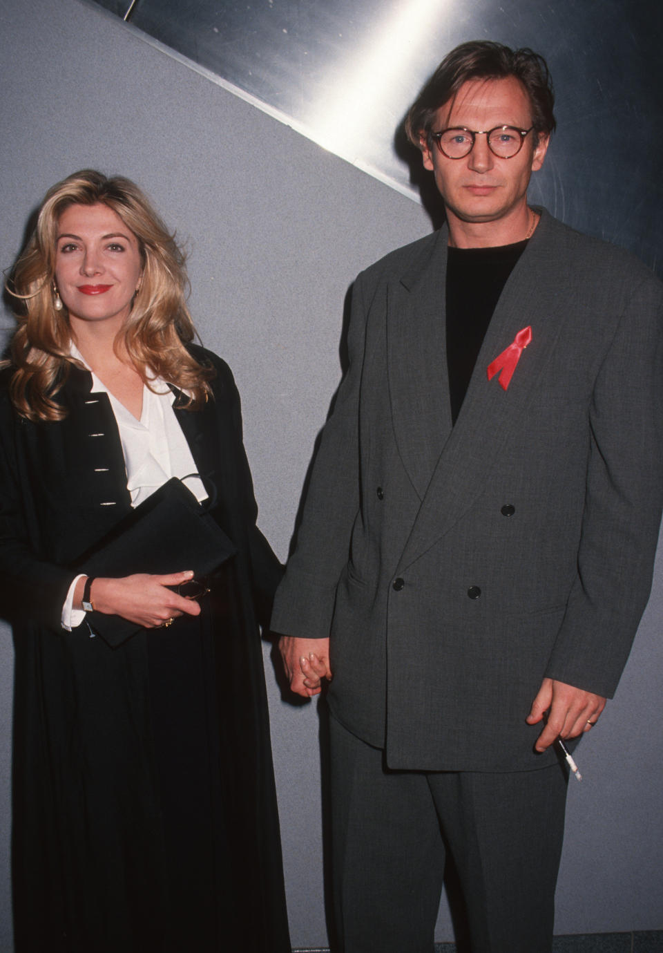 Natasha Richardson and Liam Neeson stand together holding hands at an industry event