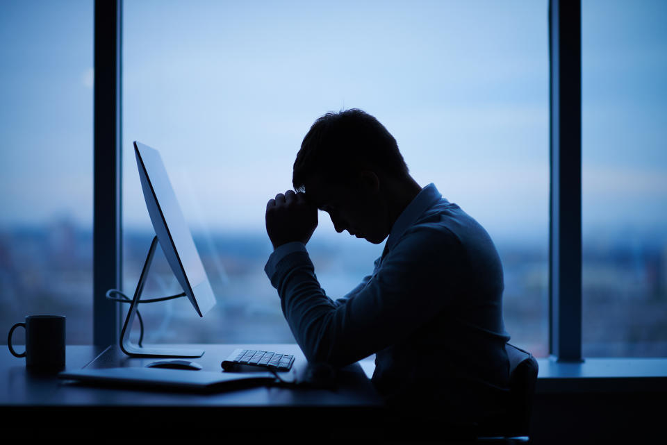 Tired or stressed businessman sitting in front of computer in office