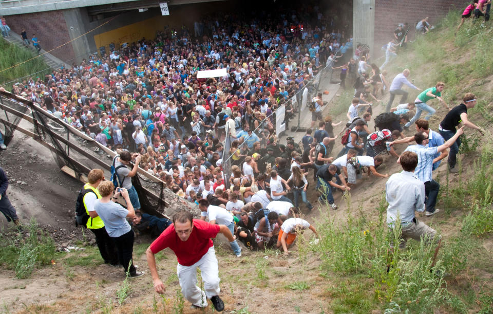 FILE - In this July 24, 2010 file picture people flee during a mass panic at a techno festival in Duisburg, Germany. German prosecutors say they have indicted 10 people on charges including involuntary manslaughter over a mass panic at the Love Parade techno music festival nearly four years ago that resulted in 21 deaths. Duisburg prosecutor Horst Bien said Wednesday Feb. 12, 2014 that four employees of the event's organizers and six city workers have been indicted. They face charges of involuntary manslaughter and bodily harm, punishable with up to five years jail time. (AP Photo/dpa,Erik Wiffers,File)