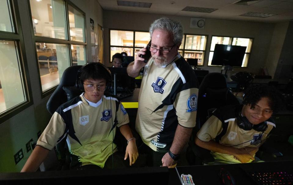 Enochs High School esports team coach Kevin Richardson, middle, talks with the Tracy High coach as they prepare to play an Overwatch video game match at Enochs High School in Modesto, Calif., Tuesday, Sept. 19, 2023.