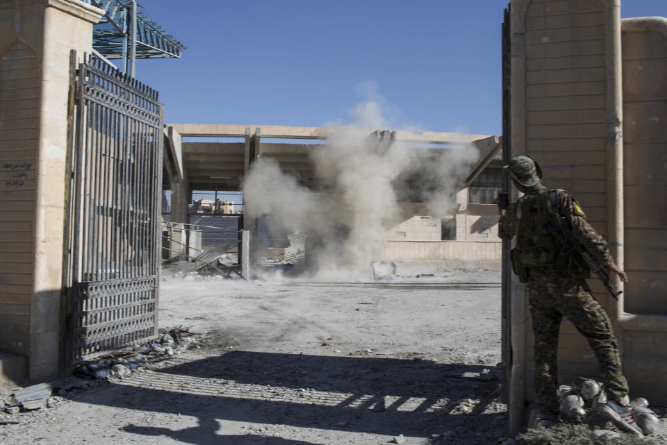 FILE - In this Oct. 18, 2017 file photo, A member of the U.S.-backed Syrian Democratic Forces SDF throws a bomb to check for more explosives as they clear the syadium that was the site of Islamic State fighters' last stand in the city of Raqqa, Syria. A year after it was routed from Iraq following a three-year devastating war that left Iraqi cities in ruin, the Islamic State group is fighting to hang on to its last enclave in Syria, engaging in deadly battles with U.S.-backed forces in the country's east near the Iraqi border. (AP Photo/Asmaa Waguih, File)