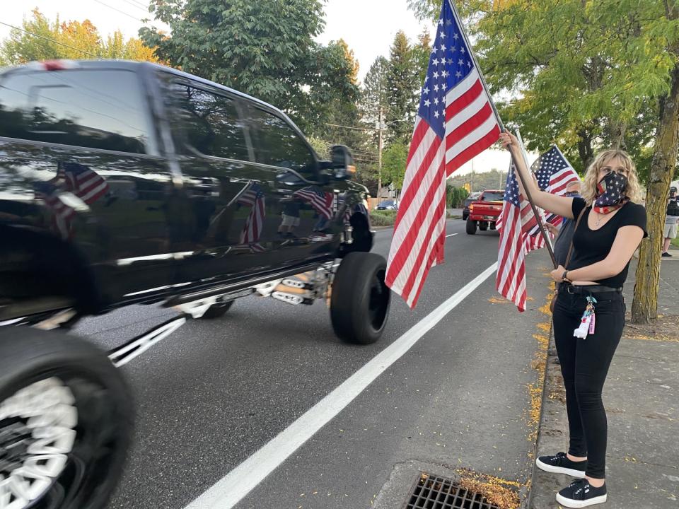 Rebecca Crymer waves a flag at passing cars in Gresham, Ore.