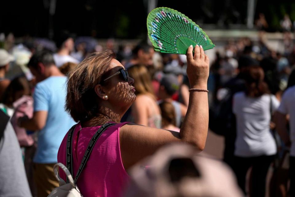 PHOTO: A tourist uses a fan to shade her face from the sun while waiting to watch the Changing of the Guard ceremony outside Buckingham Palace, during hot weather in London, July 18, 2022. (Matt Dunham/AP, FILE)