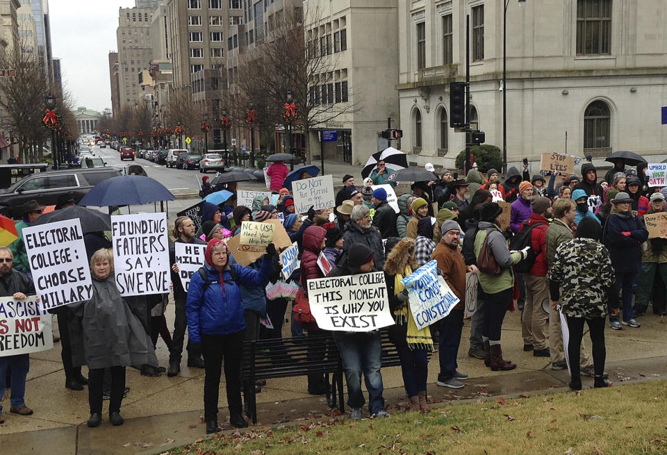 People gather outside North Carolina's antebellum Capitol building Monday, Dec. 19, 2016, in Raleigh, N.C., in hopes that enough members of the Electoral College can be swayed to deny President-elect Donald Trump the presidency. Protesters listened to speakers in a cold rain before the 15 people picked by the Republican Party cast ballots as designated by North Carolina's popular vote last month. (AP Photo/Emery Dalesio)