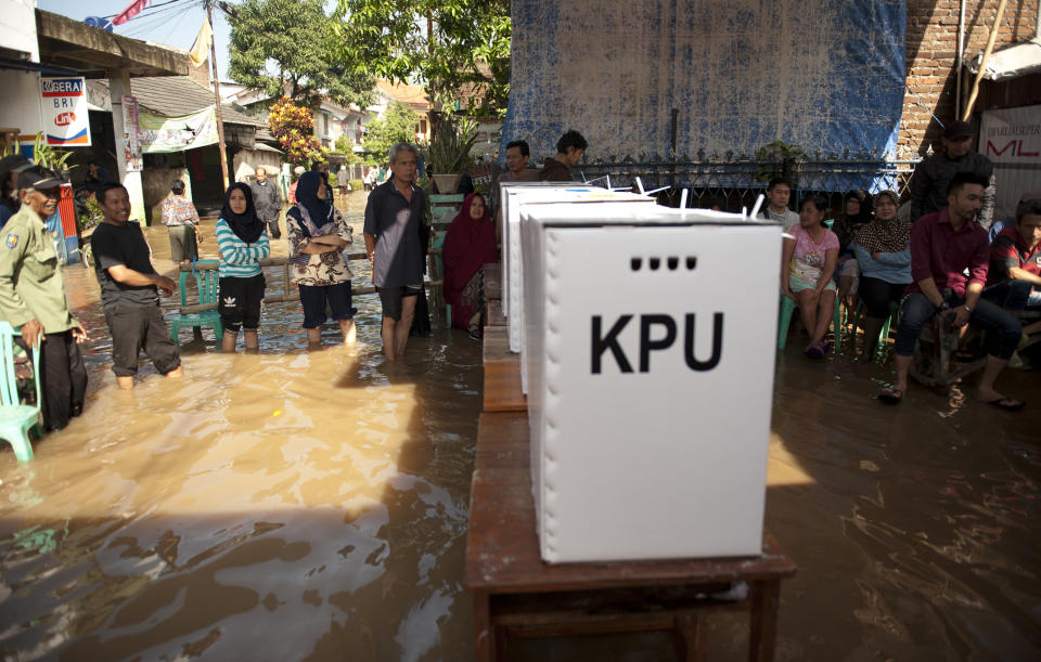 People queue up to vote at a polling station inundated by flood waters following a heavy rain in Banding, West Java, Indonesia, Wednesday, April 17, 2019. Tens of millions of Indonesians voted in presidential and legislative elections Wednesday after a campaign that pitted the moderate incumbent against an ultranationalist former general whose fear-based rhetoric warned that the country would fall apart without his strongman leadership. (AP Photo/Kusumadireza)