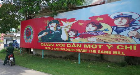A soldier stands parks his motorcycle in front of a banner at the headquarters of the Division 308 special military force in Xuan Mai town, outside Hanoi July 10, 2015. REUTERS/Greg Torode