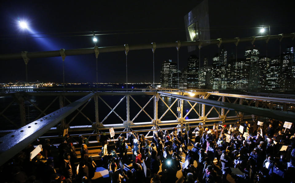 A police helicopter shines a light on protesters rallying against a grand jury's decision not to indict the police officer involved in the death of Eric Garner as they cross the eastbound traffic lanes of the Brooklyn Bridge, Thursday, Dec. 4, 2014, in New York.  A grand jury cleared a white New York City police officer Wednesday in the videotaped chokehold death of Garner, an unarmed black man, who had been stopped on suspicion of selling loose, untaxed cigarettes. (AP Photo/Jason DeCrow)