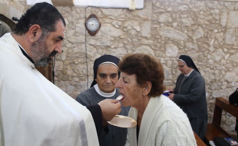 Father Iosif Skender, a Maronite priest, gives Holy Communion to a member of the congregation at the Church of St. George in Kormakitis