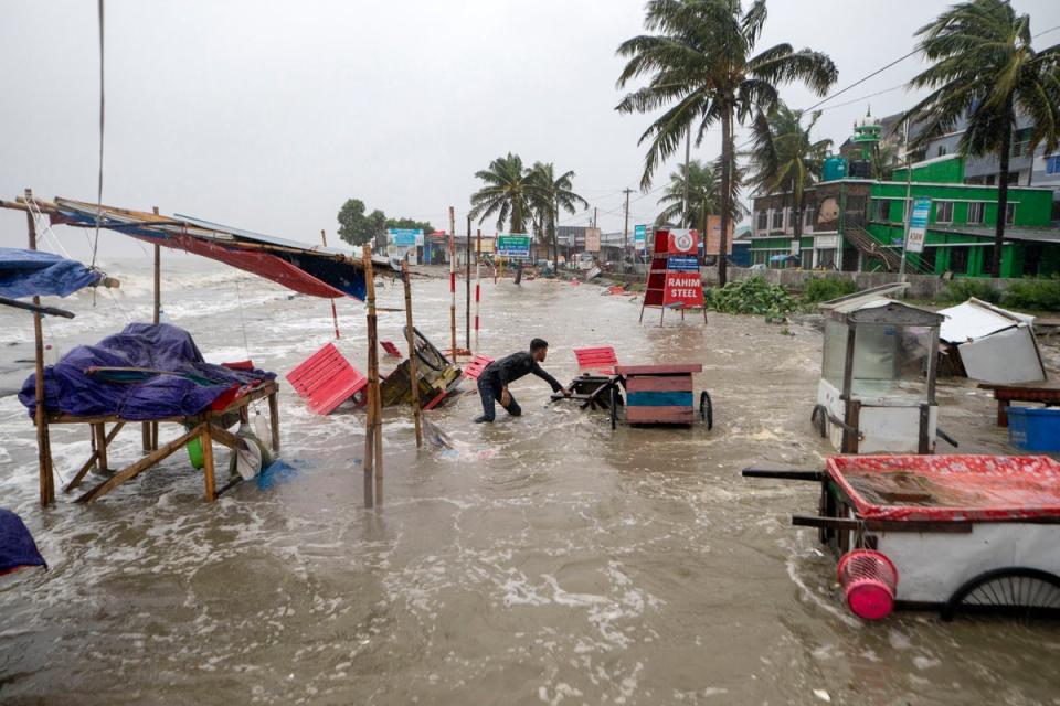 A man salvages a cart and other material as water flows on to the Kuakata beach on the coast of Bay of Bengal caused by the advancing Cyclone Remal in Barisal, Bangladesh, Sunday, 26 May 2024 (AP)