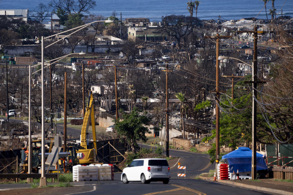 A vehicle drives by a checkpoint in front of the burn zone, Friday, Dec. 8, 2023, in Lahaina, Hawaii. Recovery efforts continue after the August wildfire that swept through the Lahaina community on Hawaiian island of Maui, the deadliest U.S. wildfire in more than a century. (AP Photo/Lindsey Wasson)