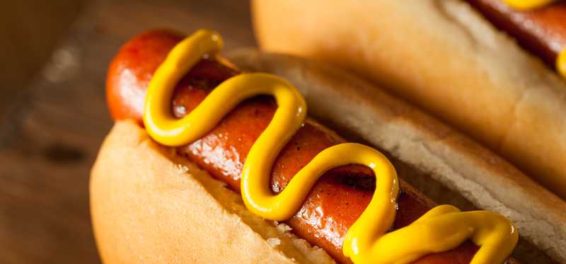 Two hot dogs are shown with mustard