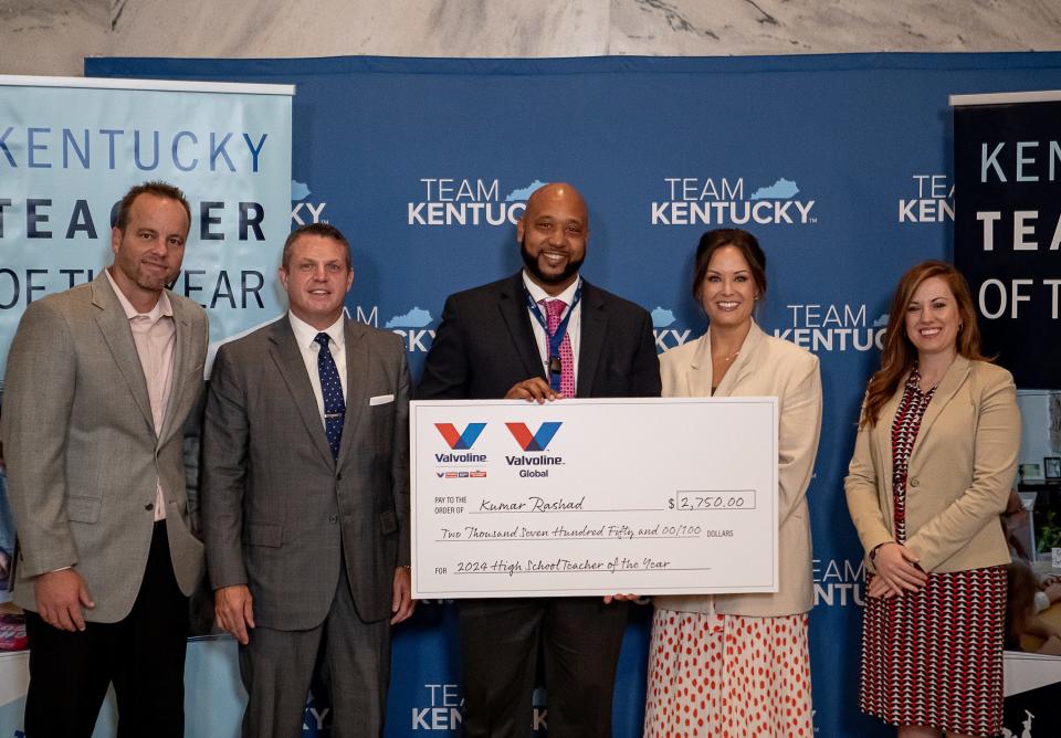 JCPS' Kumar Rashad, center, who teaches at Breckenridge Metropolitan High School holds a check alongside Commissioner of Education Jason Glass and Lieutenant Governor Jacqueline Colemen after being named the top high school teacher of the year during a ceremony in Frankfort on Wednesday morning, Sept. 13, 2023