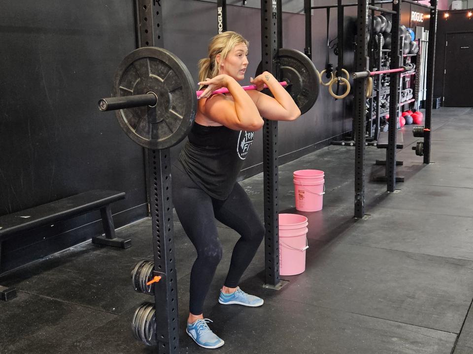 FemFit Redding founder and coach Mikilah Speer demonstrates proper squatting technique to U-Prep girls volleyball players on Tuesday, July 25, 2023.