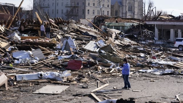 A person stands near debris cause by tornado damage in Mayfield, Ky., on Saturday, Dec. 11, 2021.