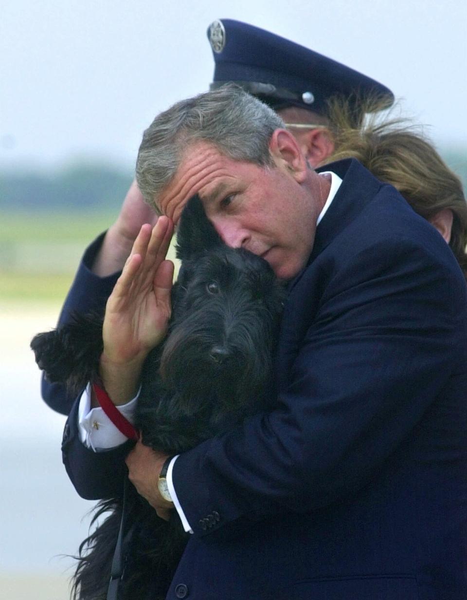 President Bush does his best to salute while holding his dog Barney as they get off of Air Force One at Andrews Air Force Base, Md.