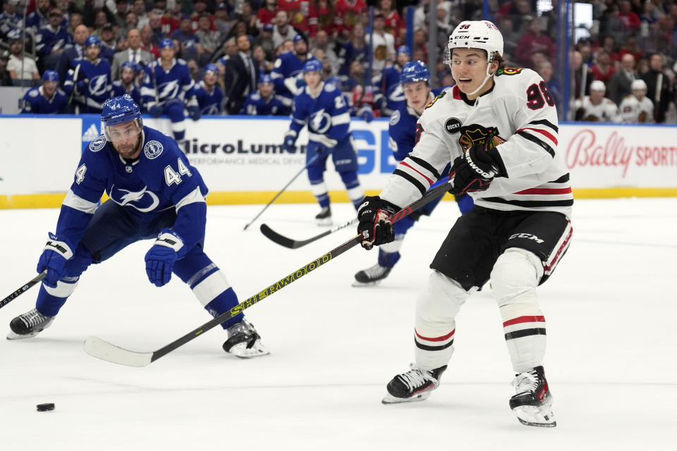 Chicago Blackhawks center Connor Bedard (98) passes the puck in front of Tampa Bay Lightning defenseman Calvin de Haan (44) during the first period of an NHL hockey game Thursday, Nov. 9, 2023, in Tampa, Fla. (AP Photo/Chris O'Meara)