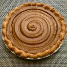 Whole pumpkin pie with a spiral pattern on a textured surface