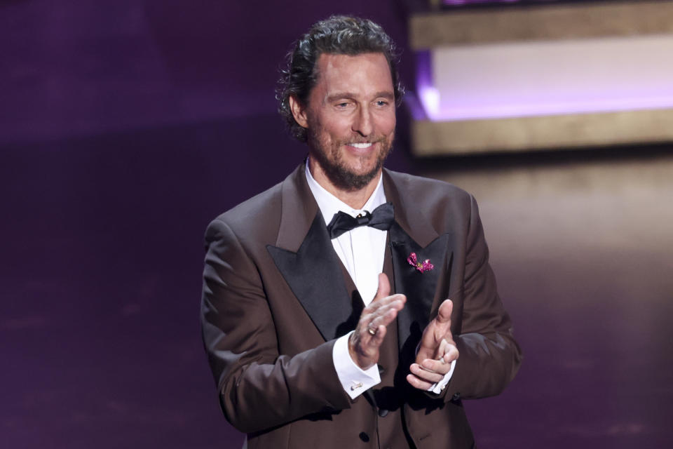 Matthew McConaughey clapping on stage in a tuxedo