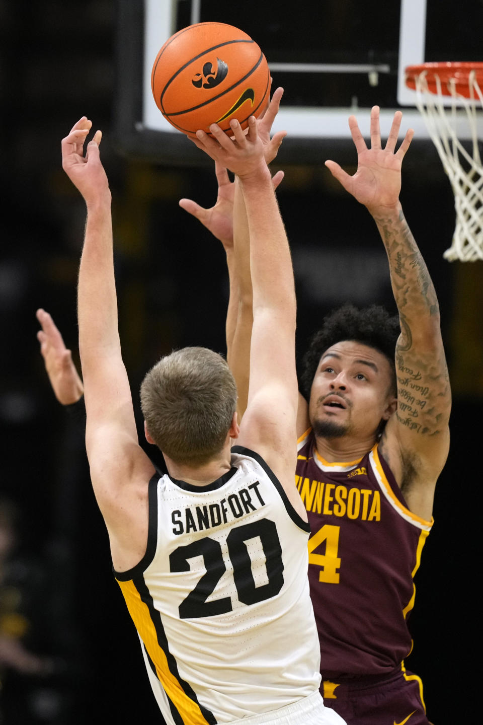 Minnesota guard Braeden Carrington (4) tries to block a shot by Iowa forward Payton Sandfort (20) during the first half of an NCAA college basketball game, Sunday, Feb. 11, 2024, in Iowa City, Iowa. (AP Photo/Charlie Neibergall)