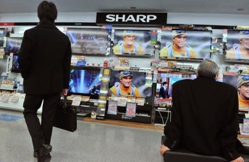 Customers look at Sharp televisions in a Tokyo store. The company is to slash 5,000 jobs by March, its first cuts since 1950 as it is hit by a prolonged slump in its key television and liquid crystal display sectors