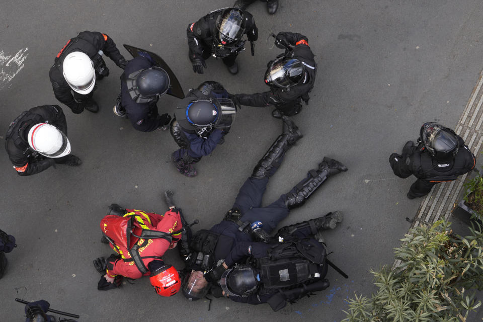 A riot police officer is being taken care by an emergency worker during demonstration, Thursday, April 13, 2023 in Paris. Protesters opposed to President Emmanuel Macron's unpopular plan to raise the retirement age in France marched Thursday in cities and towns around France in a final show of anger before a decision by the Constitutional Council on whether the measure meets constitutional standards. (AP Photo/Thibault Camus)