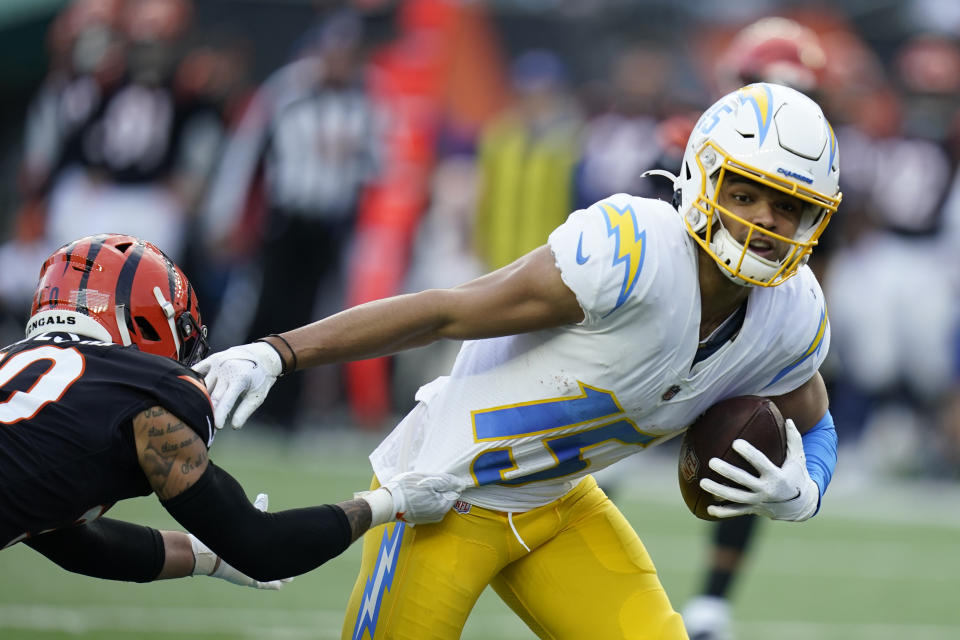 Los Angeles Chargers' Jalen Guyton (15) runs out of the tackle of Cincinnati Bengals' Jessie Bates (30) during the second half of an NFL football game, Sunday, Dec. 5, 2021, in Cincinnati. (AP Photo/Michael Conroy)