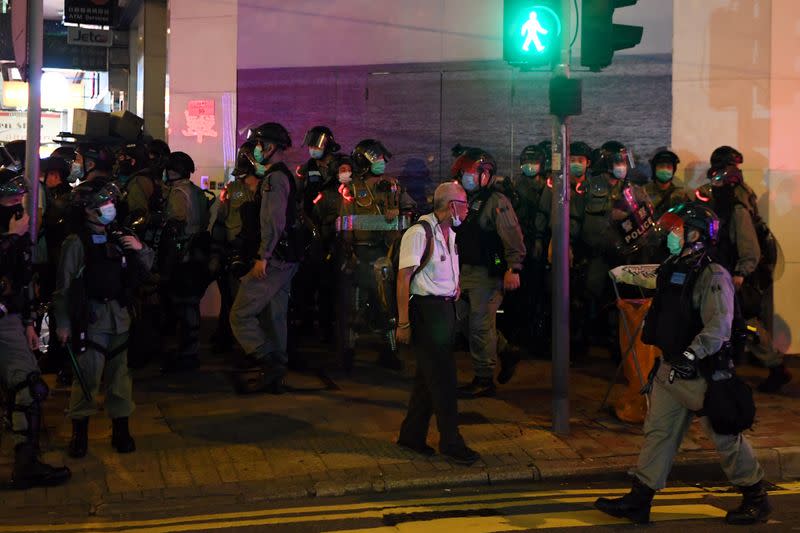 Man waits to cross the street near police officers during a protest in Hong Kong